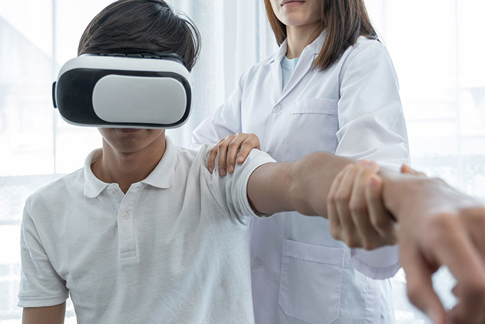 Hand-Arm therapy with PABLO system: Patient wearing VR headset, therapist guides patient's upper extremity movements